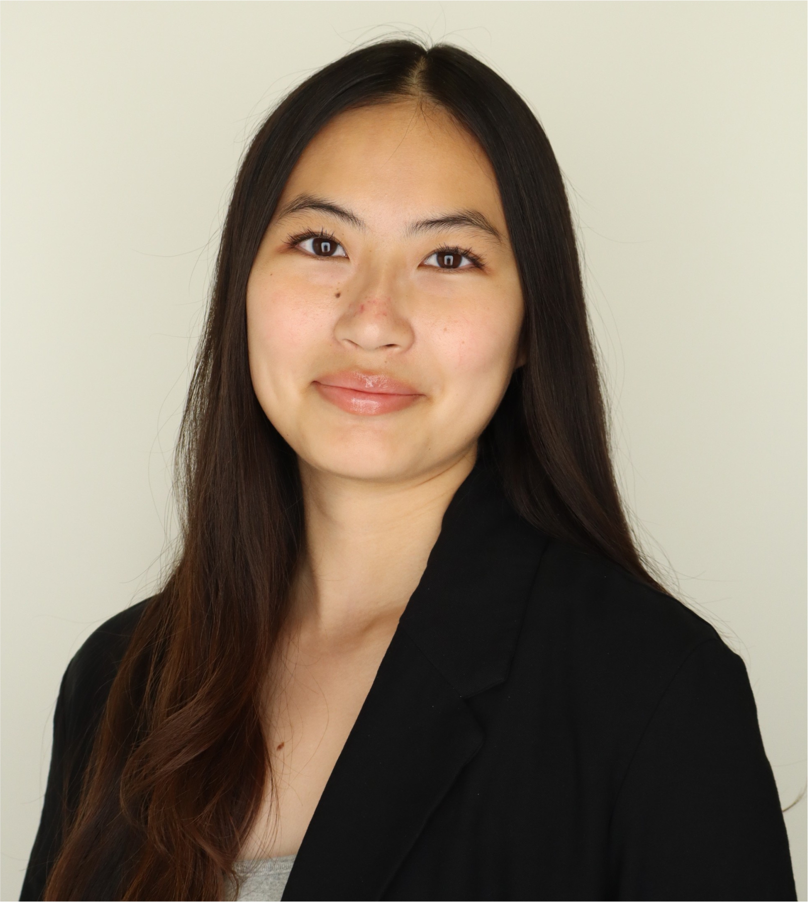 Professional headshot of smiling woman with long dark hair in black blazer.
